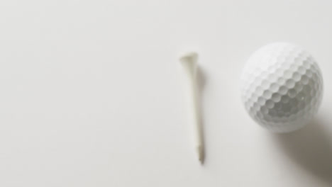 Close-up-of-golf-tee-and-ball-on-white-background,-copy-space,-slow-motion
