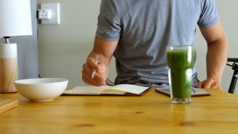 man writing on a diary in kitchen 4k