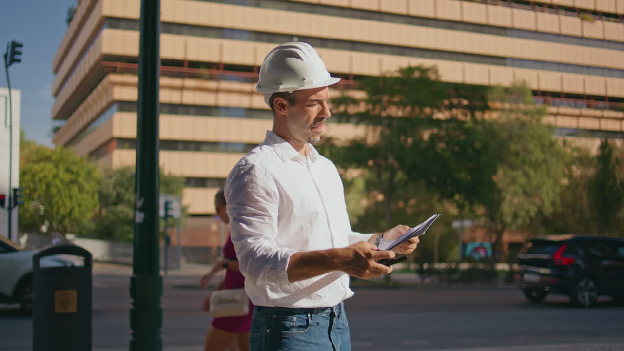 Hardhat man using walkie-talkie giving instructions to workers in modern city