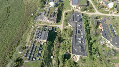 aerial tilt down to solar panels on rooftops on beautiful earthship homes