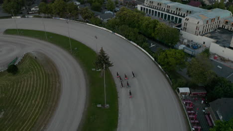 Toma-De-Seguimiento-De-La-Carrera-De-Caballos-En-La-Pista-De-Tierra-Galopando-Rápido,-Vista-Aérea-De-Pájaros