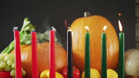 composition of seven candles being blown off over halloween pumpkins and vegetables