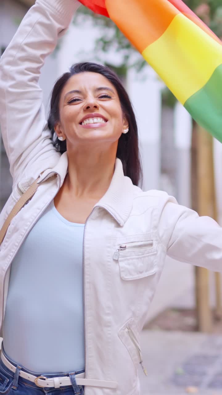 Mulher feliz acenando e beijando a bandeira do arco-íris do orgulho LGBTQIA+ na rua da cidade