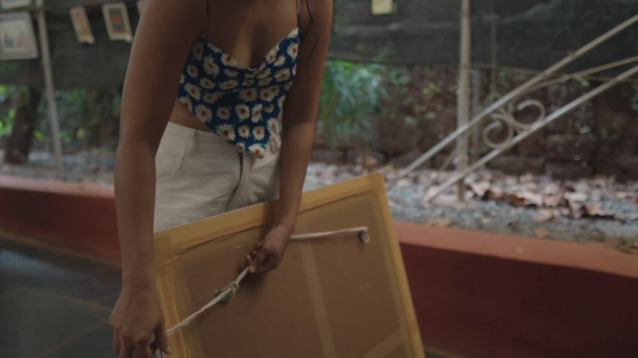 이 상세한 슬로우 모션 촬영에서 젊은 예술가가 미술 갤러리에서 전시하기 위해 그녀의 예술 작품을 전문적으로 준비합니다.