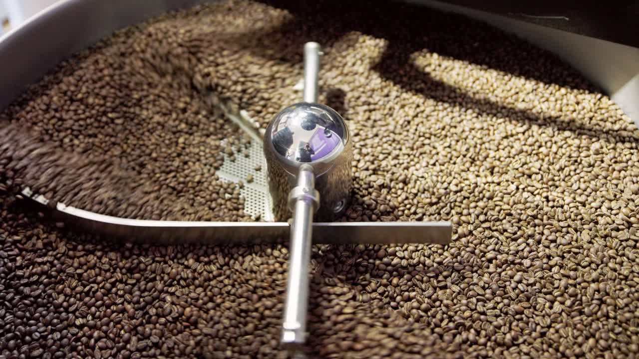 широкий замедленный вид кофейных зерен, падающих через обжигание барабанной машины