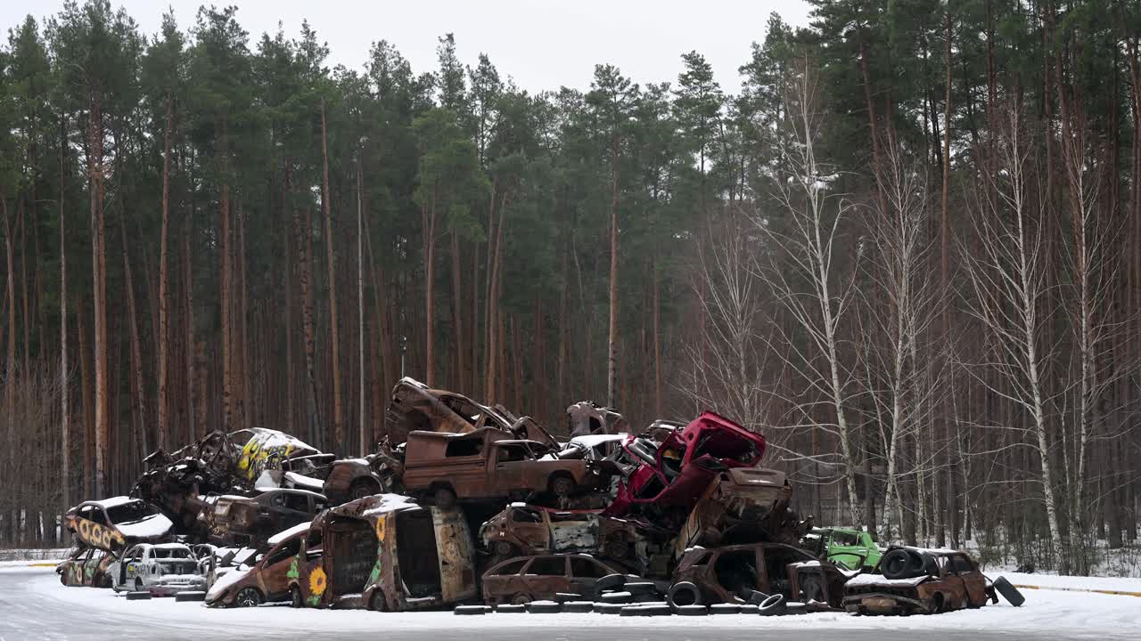 In Irpin, Ukraine, a pile of burnt and wrecked cars is stacked together on a winter day, following the battles between Ukrainian and Russian forces in the ongoing war.