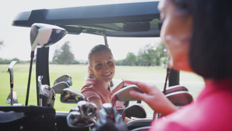 two mature female golfers sitting in buggy course on course and talking