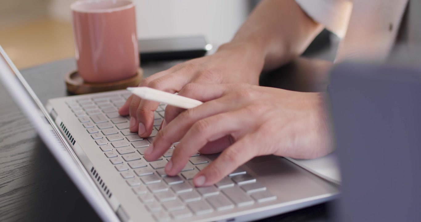 Uomo afroamericano che appoggia le mani sul laptop, digitando e toccando con uno stilo bianco, lavorando alla scrivania.