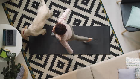 Woman-Exercising-at-Home-while-Dog-Walking-Around