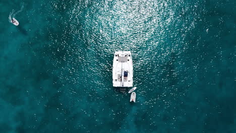 TOPDOWN-drone-shot-of-a-sailing-yacht-in-the-turquoise-waters-of-a-tropical-island