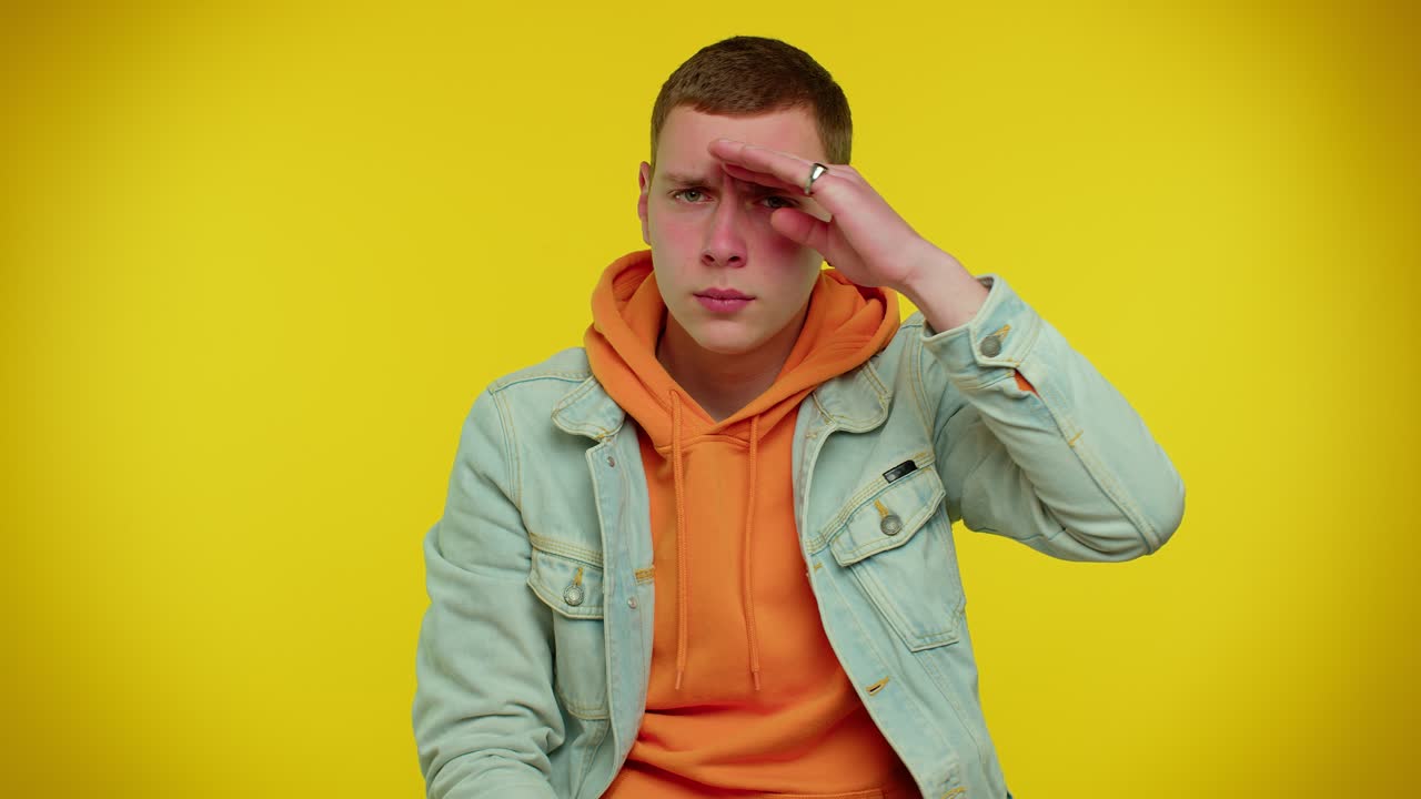 hombre sosteniendo la mano por encima de los ojos frente, mirando, mirando a su alrededor, esperando y buscando a alguien