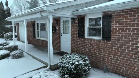 snow-dusted single-story brick house with a front yard and bare trees