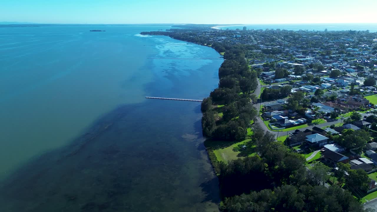 Drone aerial landscape of Long Jetty boardwalk pier wharf in Tuggerah Lake water catchment lagoon river with suburban town rural housing neighbourhood Central Coast tourism Australia travel nature