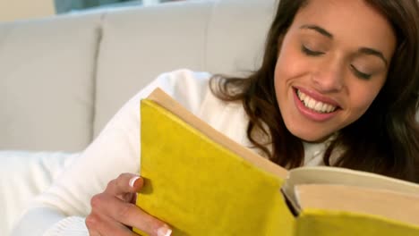 woman reading book on couch