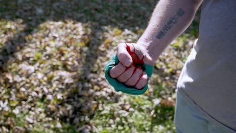 mano sangrante con torniquete improvisado aprieta un puño, rastreando tiro, cámara lenta