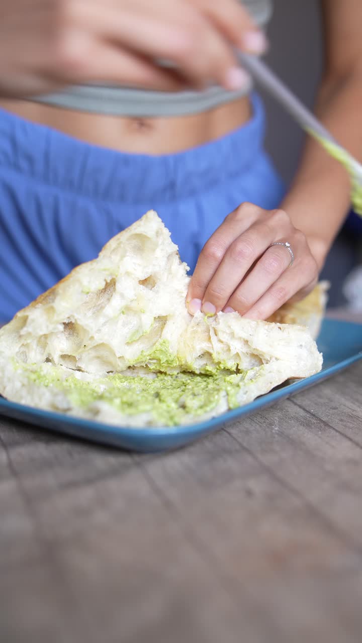 Woman eating a pesto bread sandwich