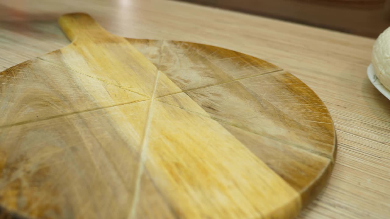 클로즈업 요리사는 갈색 테이블 위에 둥근 나무판을 놓습니다.