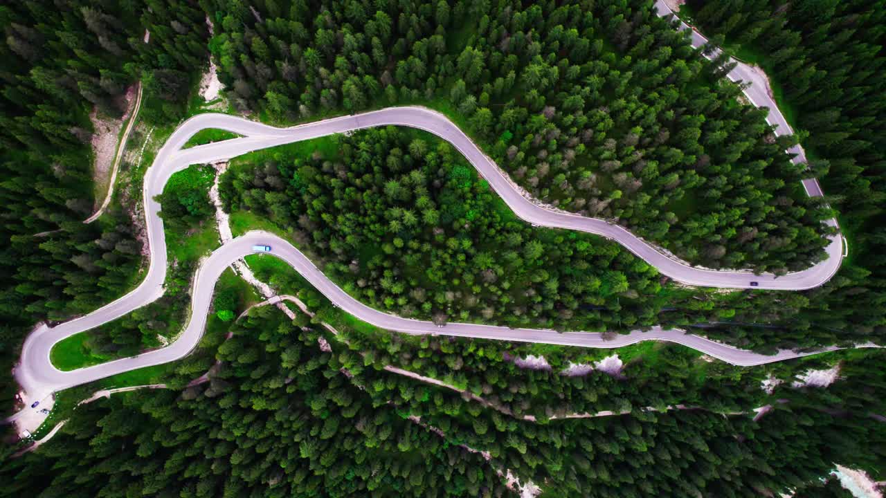 vehículos maniobrando a través de los curvos pasos de montaña en los alpes - toma aérea de arriba hacia abajo
