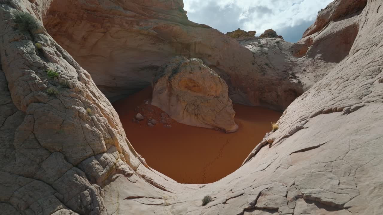 Ripresa da drone della conca di arenaria 'Cosmic Ashtray' con sabbia arancione, circondata dal terreno desertico dello Utah.