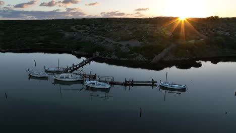 Puesta-De-Sol-En-El-Puerto-Natural-De-Sa-Nitja,-Menorca,-Barcos-En-Aguas-Azul-Oscuro