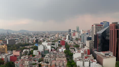 Elevated-view-of-various-building-in-town.-Tall-business-buildings-neighbors-with-lower-residential-houses.-Drone-camera-slowly-descending-in-time-before-rain.