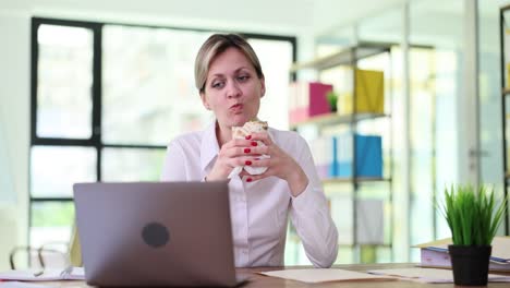 Businesswoman eating sandwich at her desk