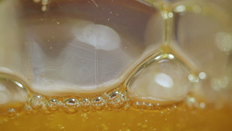 macro close up of viscous bubbles expanding and floating on top of an abstract orange liquid