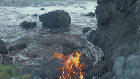 fire burning on rocky seaside shoreline. ascending shot