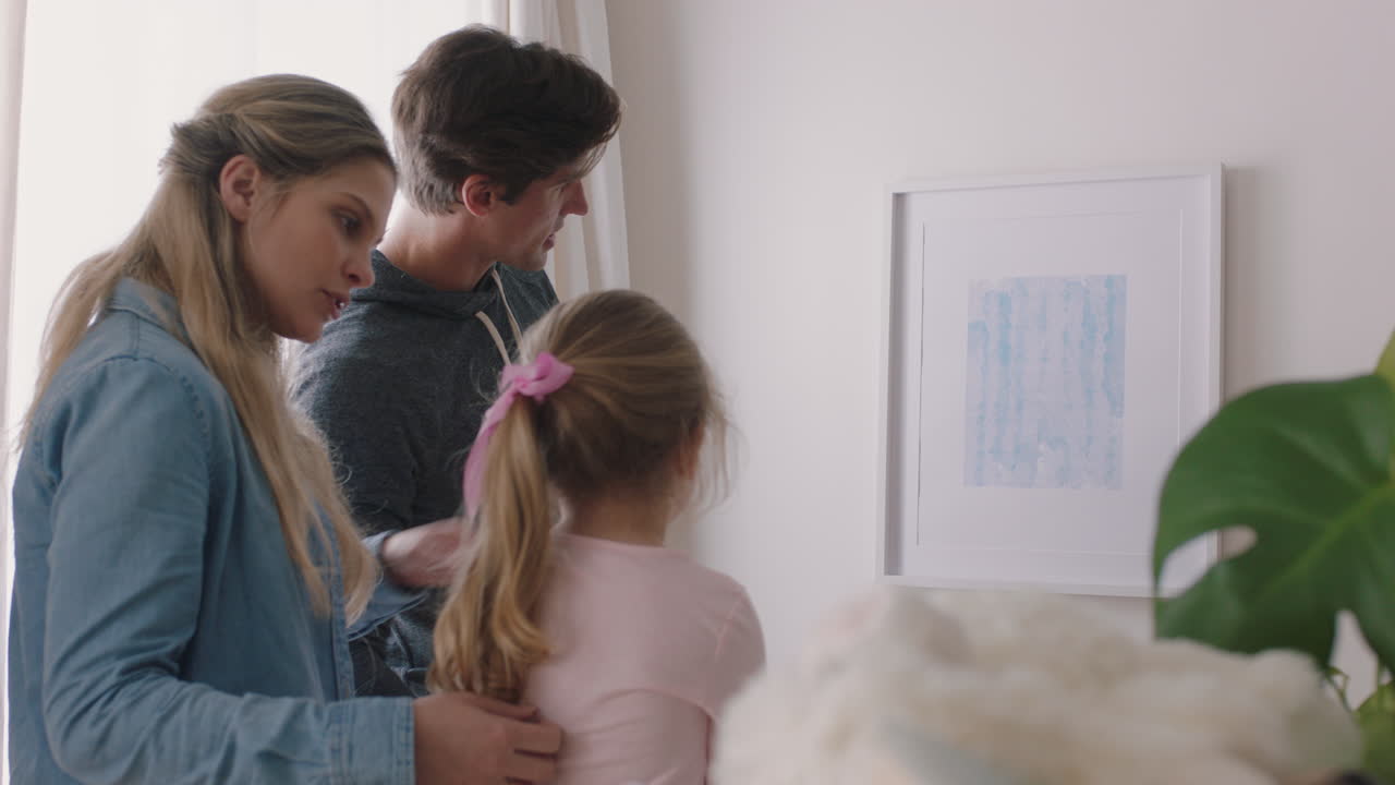 행복한 가족이 새로운 집으로 이사합니다. 주인들은 사진을 걸고 아이들과 함께 집을 꾸미고 있습니다. 젊은 부부는 아이들과 함께 부동산 투자를 즐기고 있습니다. 4k 영상