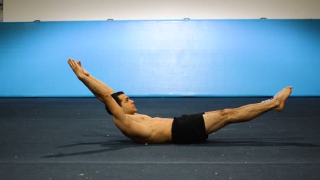 a guy doing a static hold in a gymnastics gym working out his abs and core muscles still shot