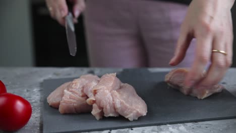 mujer preparando pecho de pollo crudo