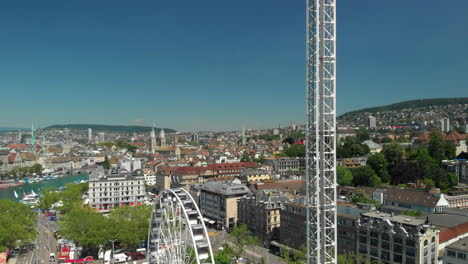tiro de grúa de drones aéreos que muestra la rueda de la fortuna del parque de atracciones y la torre de caída libre con la ciudad de zúrich, suiza en el fondo durante zürichfest