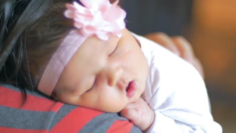 over the sholder view of a mother holding her sleeping newborn baby on her shoulder