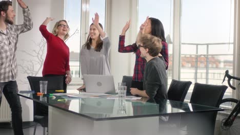multiethnic group of business people making a group high five in their conference room