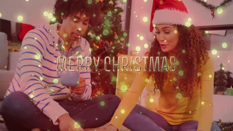 merry christmas text animation over couple sitting by christmas tree