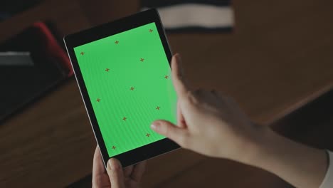 mujer gestando con la mano en la pantalla verde de la tableta. mujer deslizando el dedo por la pantalla de la tableta