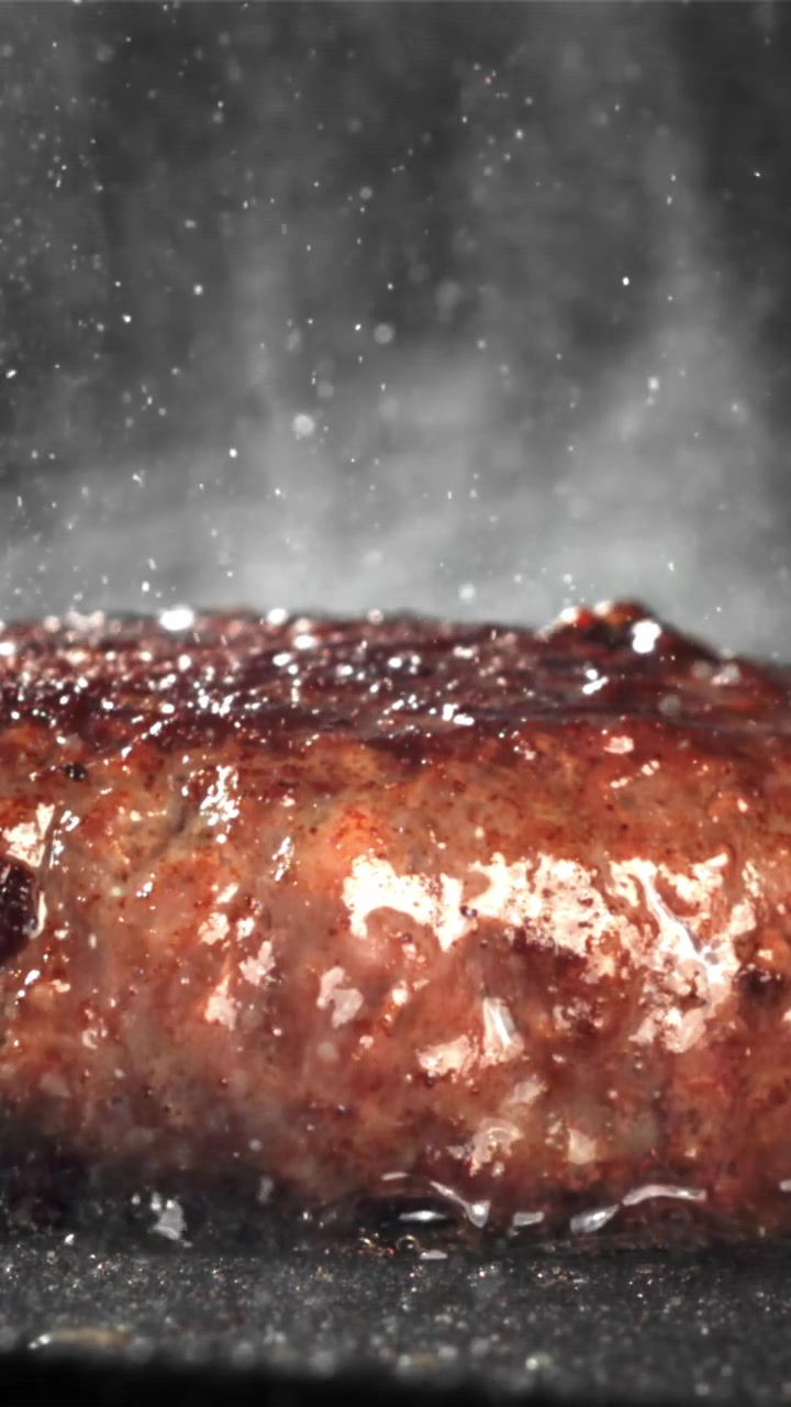 Nærbillede af en hakkebøf, der syder på en varm grill