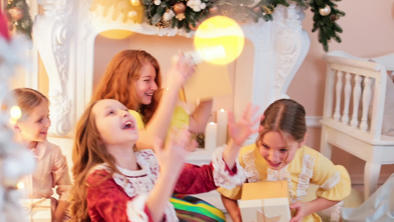 Happy joyful Caucasian teenage girls having fun in photo studio. Kids toss present boxes smiling happily. Christmas season concept.