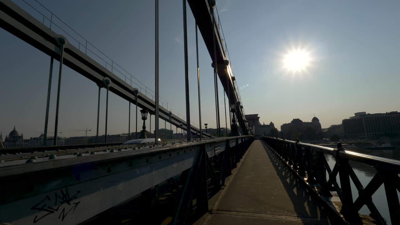 caminando por el puente de las cadenas al amanecer, budapest, hungría