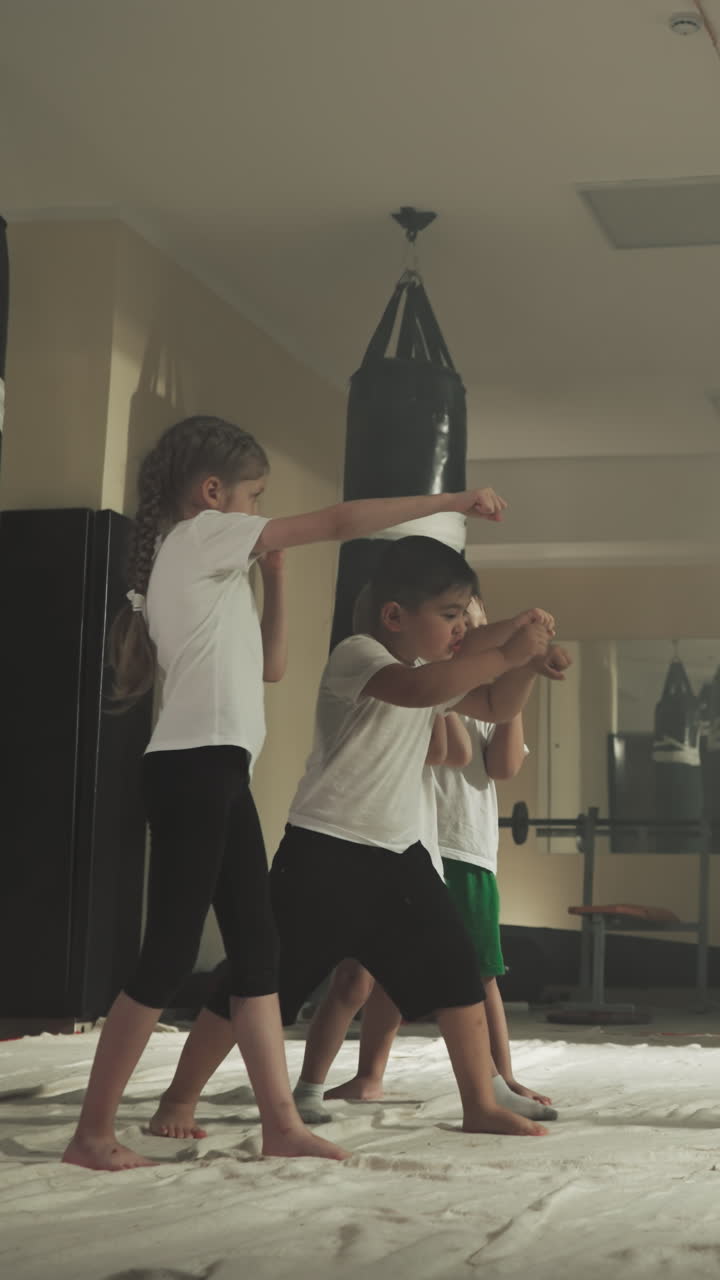 아이들은 전투 학교에서 트레이너와 함께 주먹을 맞는다. 어린 아이들은 체육관에서 젊은 강사와 함께 자기 방어 기법을 배니다. 느린 동작. 권투 스포츠.