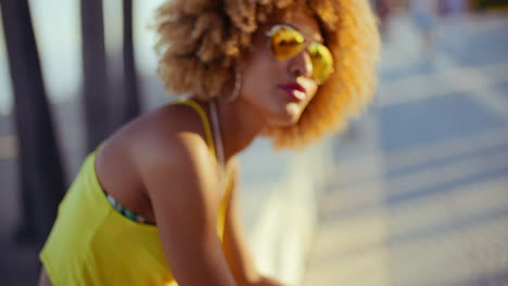 chica sensual con afro descansando en el paseo marítimo