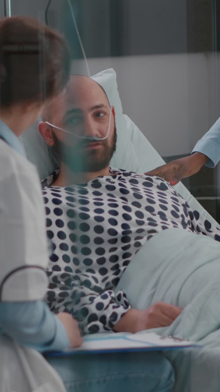Vertical video: Patient discussing with doctors while lying in bed during sickness recovery