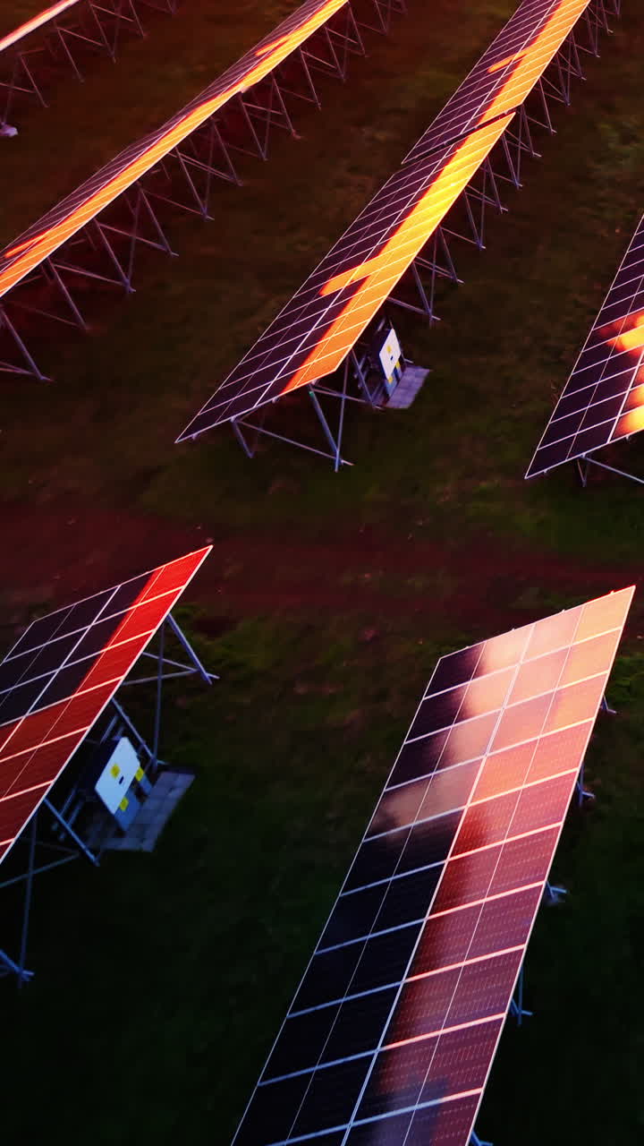 Primo piano di moduli fotovoltaici su telai metallici con apparecchiature elettroniche sottostanti durante le condizioni di illuminazione dell'ora d'oro. Struttura di montaggio per pannelli solari al tramonto. Video verticale.