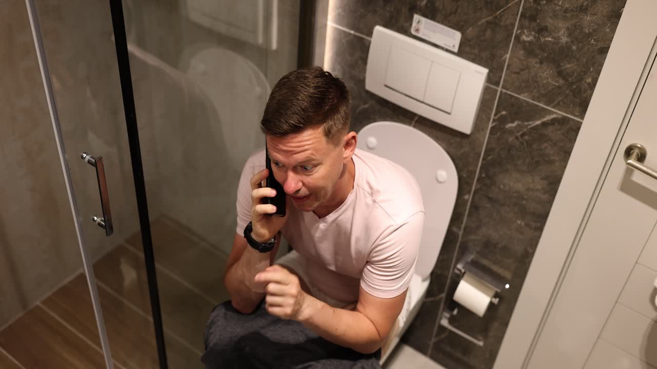 Man talking on phone while using toilet
