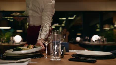 Restaurant-waiter-putting-plates-on-table.-Romantic-couple-enjoy-serving-in-bar.