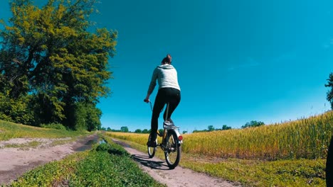 young woman riding vintage bicycle along a rural road in a village