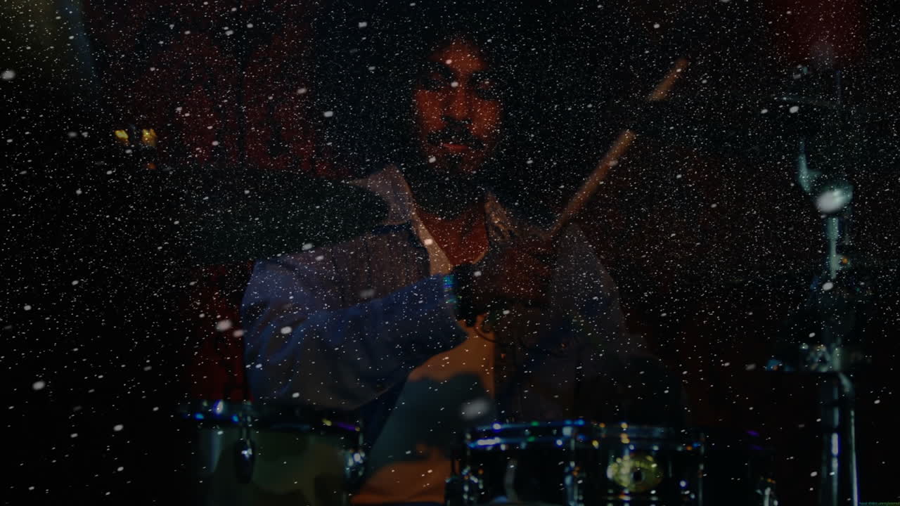 Male drummer performing on music stage, showing animated confetti particles and colored lights