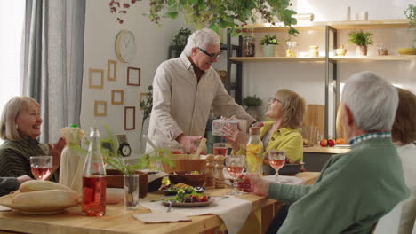 Elderly-Man-Giving-Gift-to-Happy-Wife-at-Birthday-Dinner