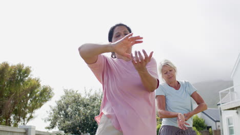 Zwei-Konzentrierte,-Vielfältige-ältere-Frauen-Praktizieren-Yoga-Im-Sonnigen-Garten,-Zeitlupe,-Kopierraum