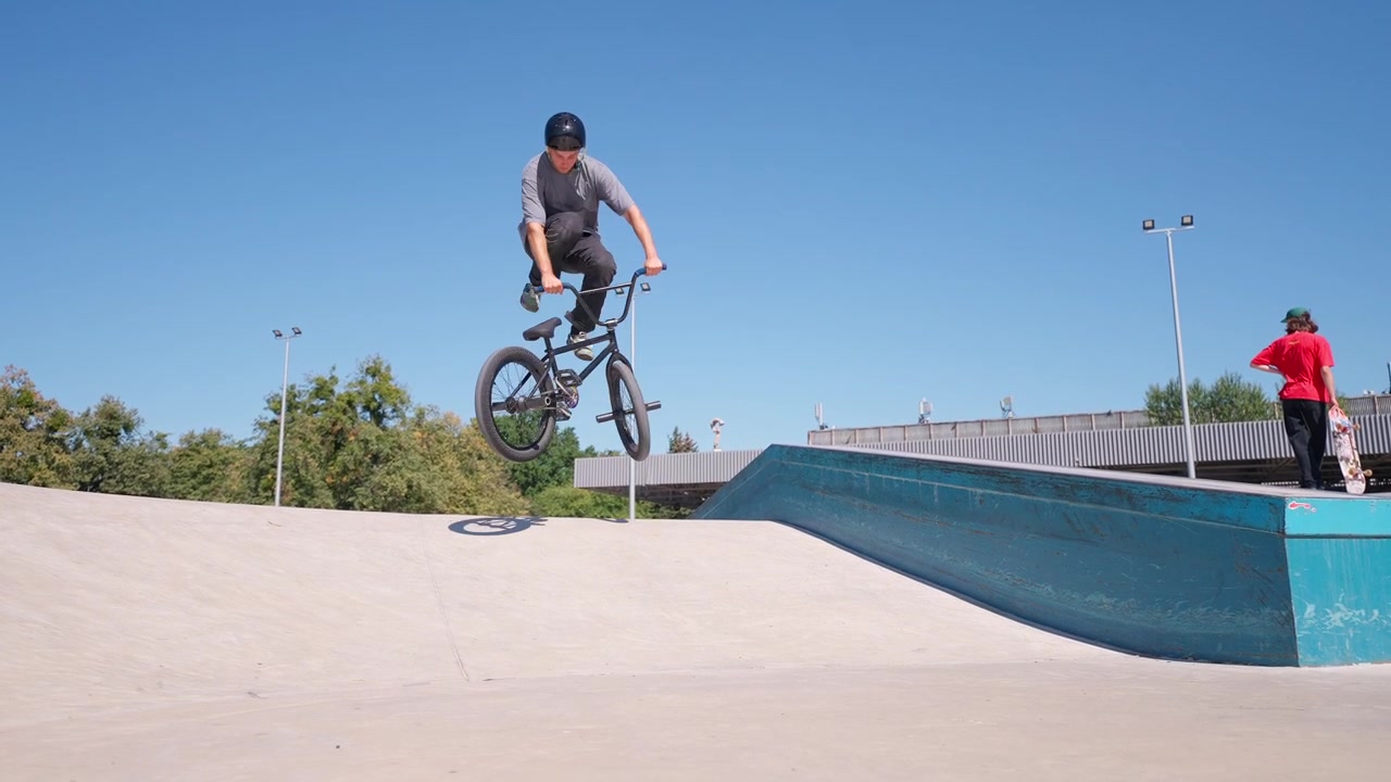 Ciclista BMX che esegue un salto e un trucco di equilibrio allo skatepark.